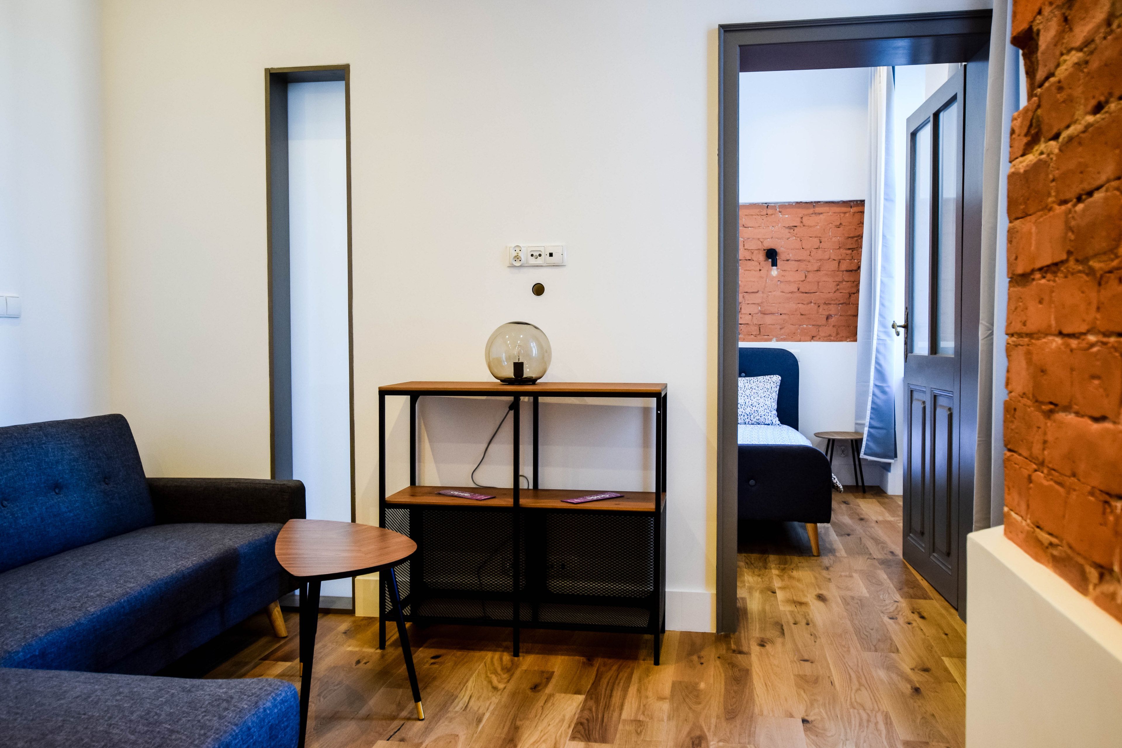 Een moderne woonkamer met een bank, een klein tafeltje en een console met een lamp.