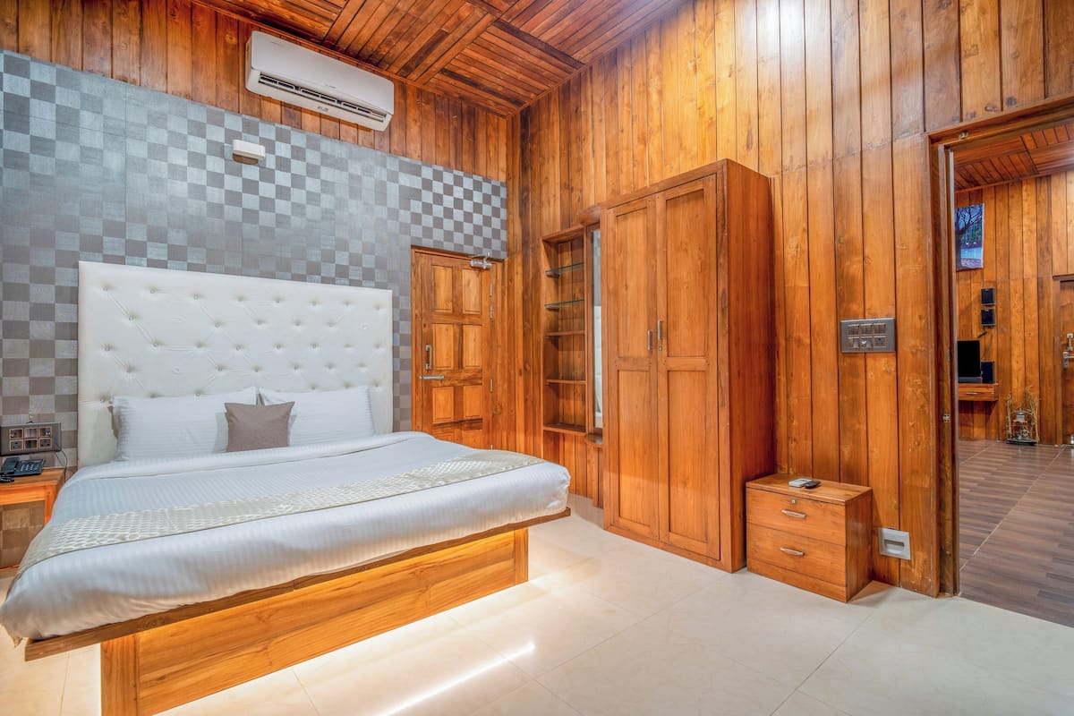 Quarto com uma cama grande, paredes de madeira, painel de parede quadriculado e um armário embutido.