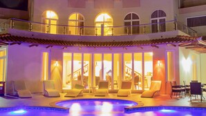 Un bâtiment moderne à deux étages, doté d’une piscine, d’un espace extérieur aménagé et d’une entrée bien éclairée.