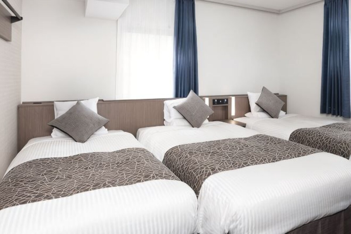 Una habitación de hotel con cuatro camas, cada una con almohada y colcha estampada.
