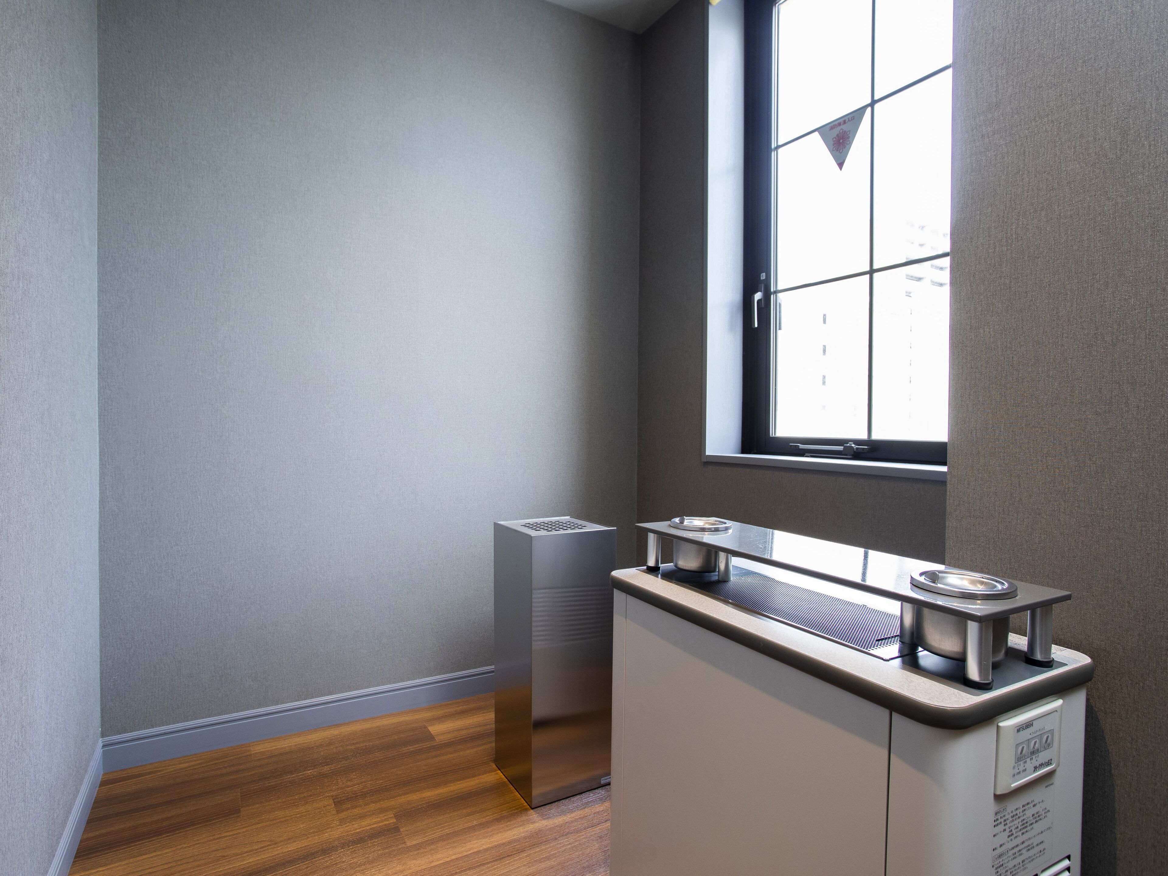 A corner of a room with a window, a radiator, and a kitchenette area.