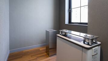 A corner of a room with a window, a radiator, and a kitchenette area.