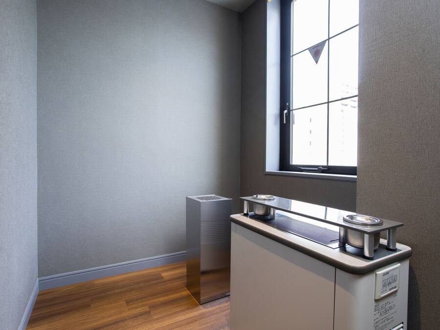 A corner of a room with a window, a radiator, and a kitchenette area.