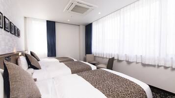 Habitación de hotel con dos camas, una mesita y una silla.