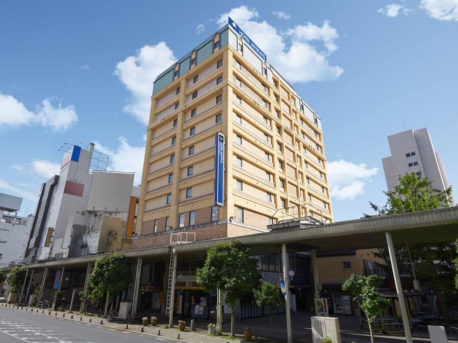 A multi-story hotel with a modern design, featuring a prominent entrance and a covered outdoor area with seating.