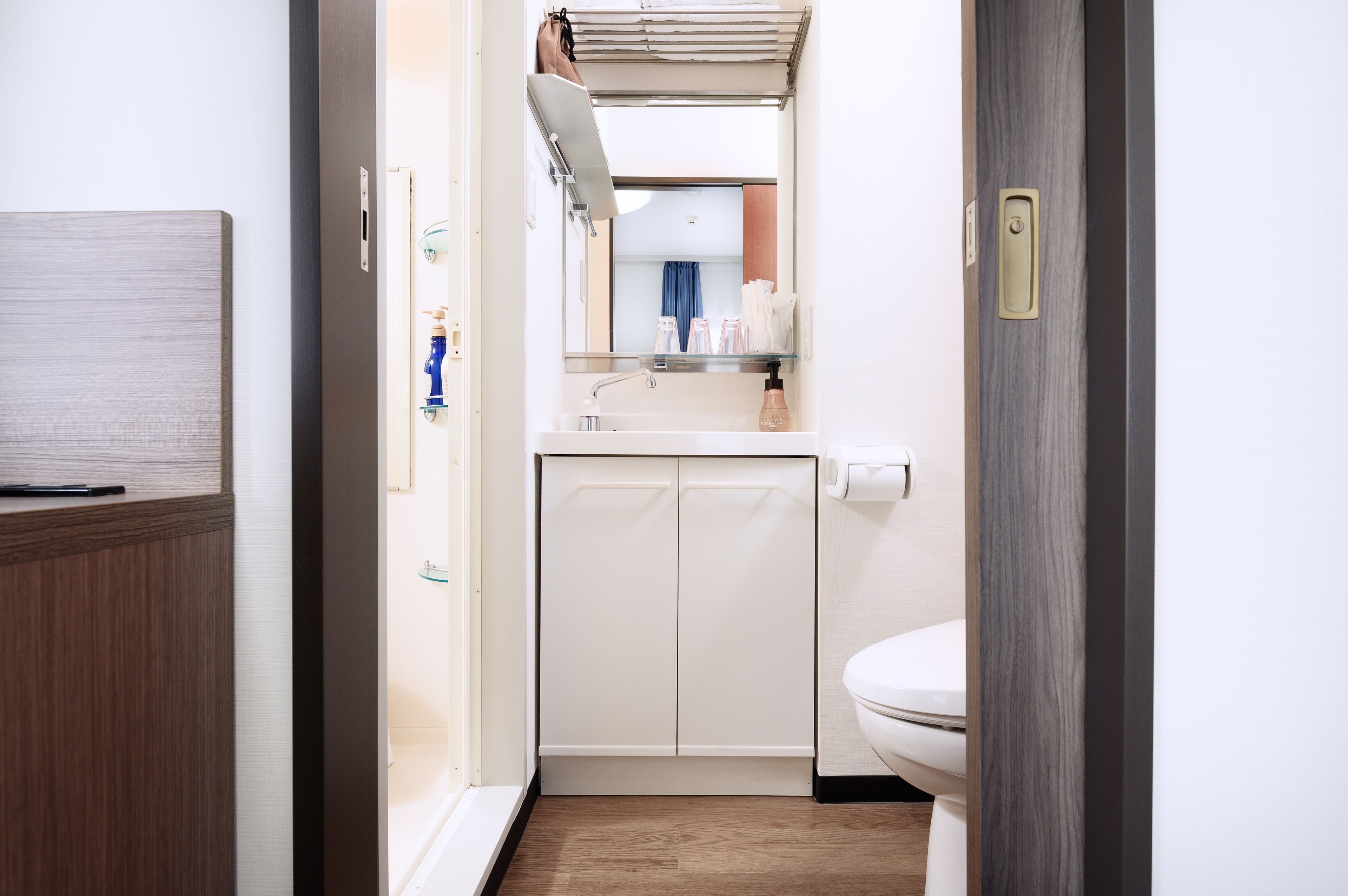 A compact bathroom with a toilet, a sink with a mirror, and a towel rack.