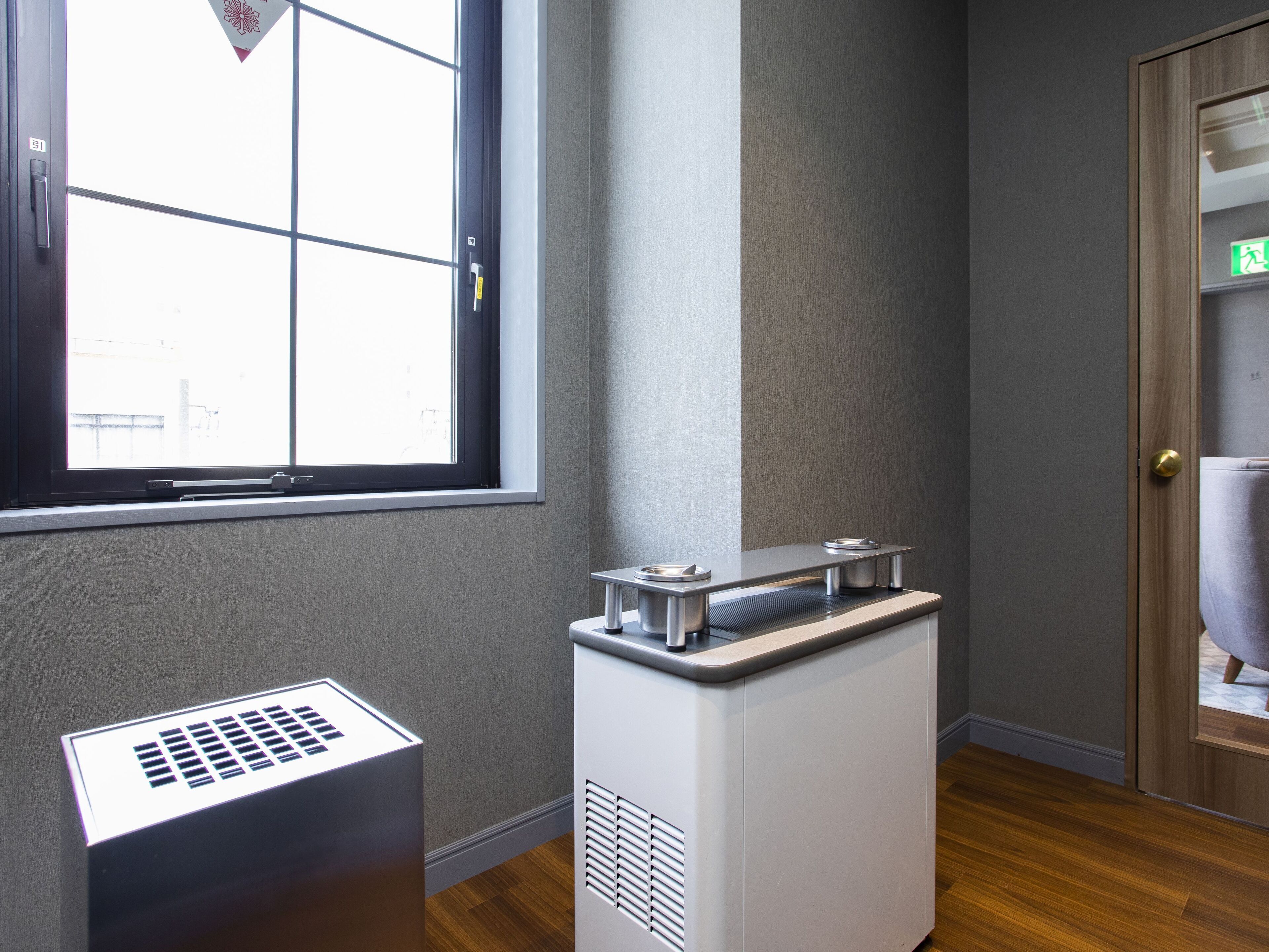 Una habitación con ventana, dispensador de agua y puerta.