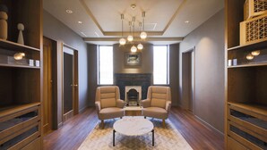 A modern living room with two armchairs, a round coffee table, and built-in wooden shelving.