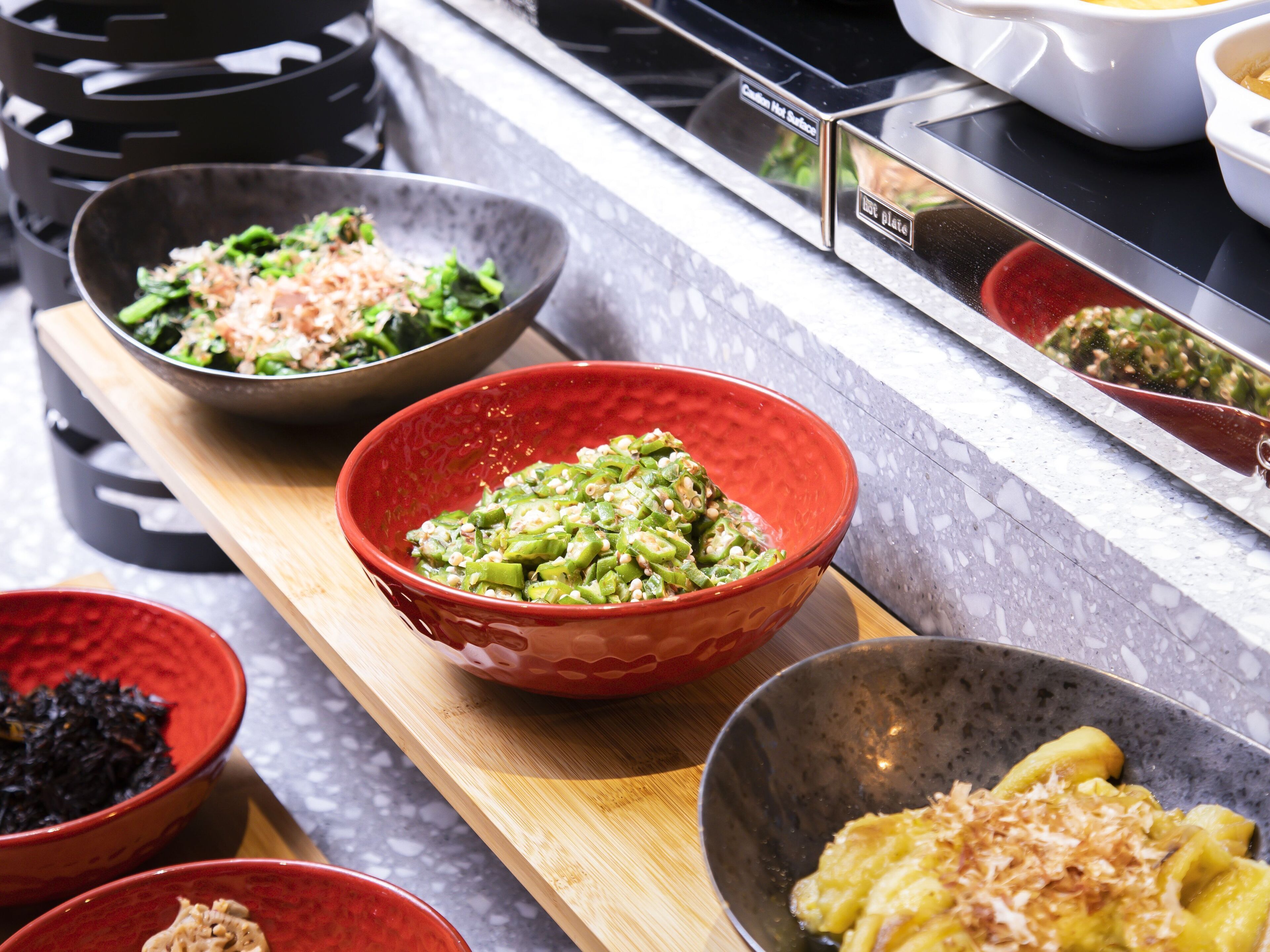 A kitchen counter with various bowls containing different dishes, a stove, and a microwave.