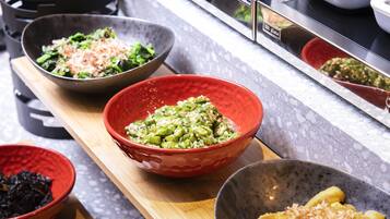 A kitchen counter with various bowls containing different dishes, a stove, and a microwave.