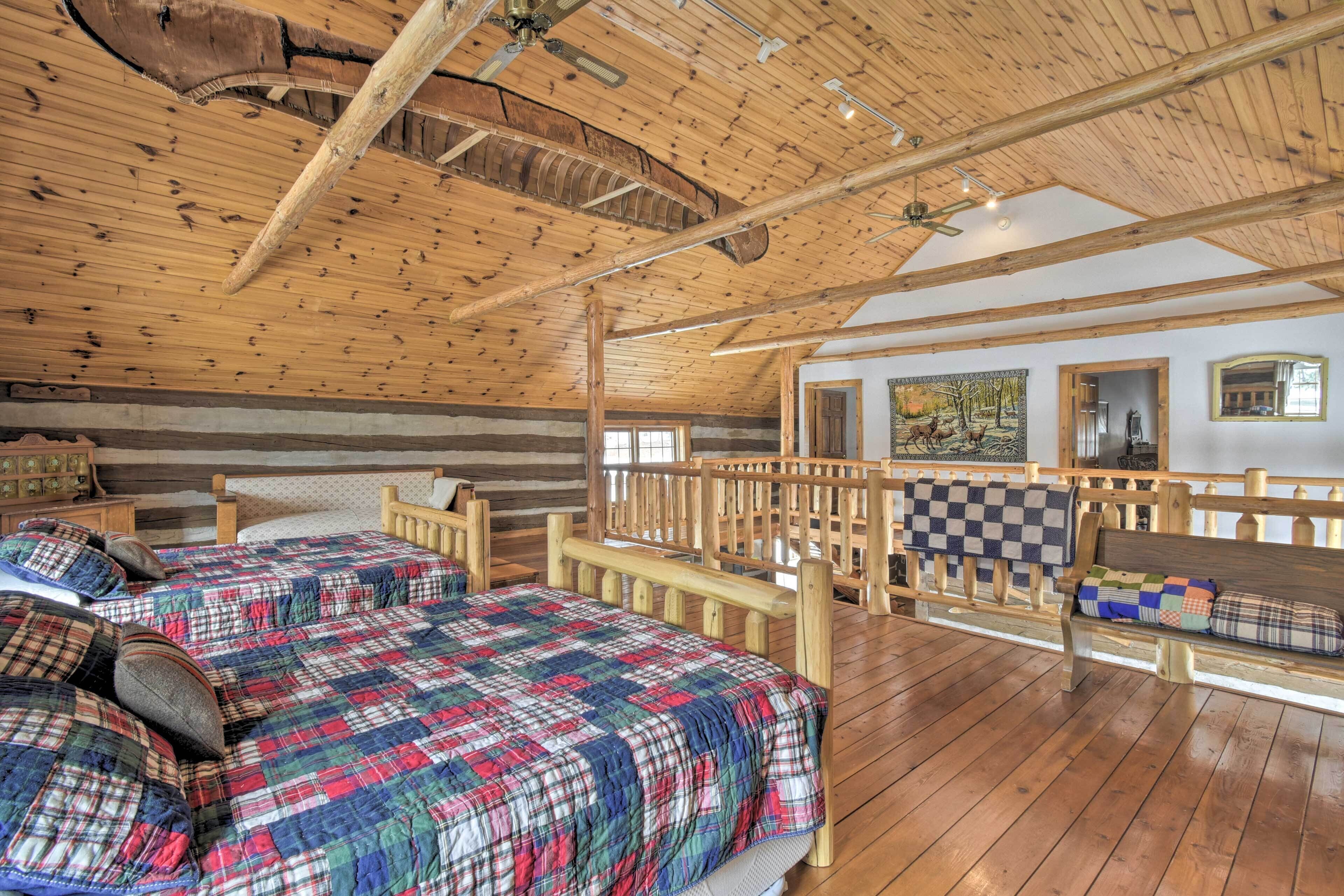 Une chambre dans une cabane en rondins, avec un grand lit, un banc en bois et une couverture à carreaux.