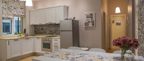 A modern kitchen with white cabinets, a central island, and pendant lighting.