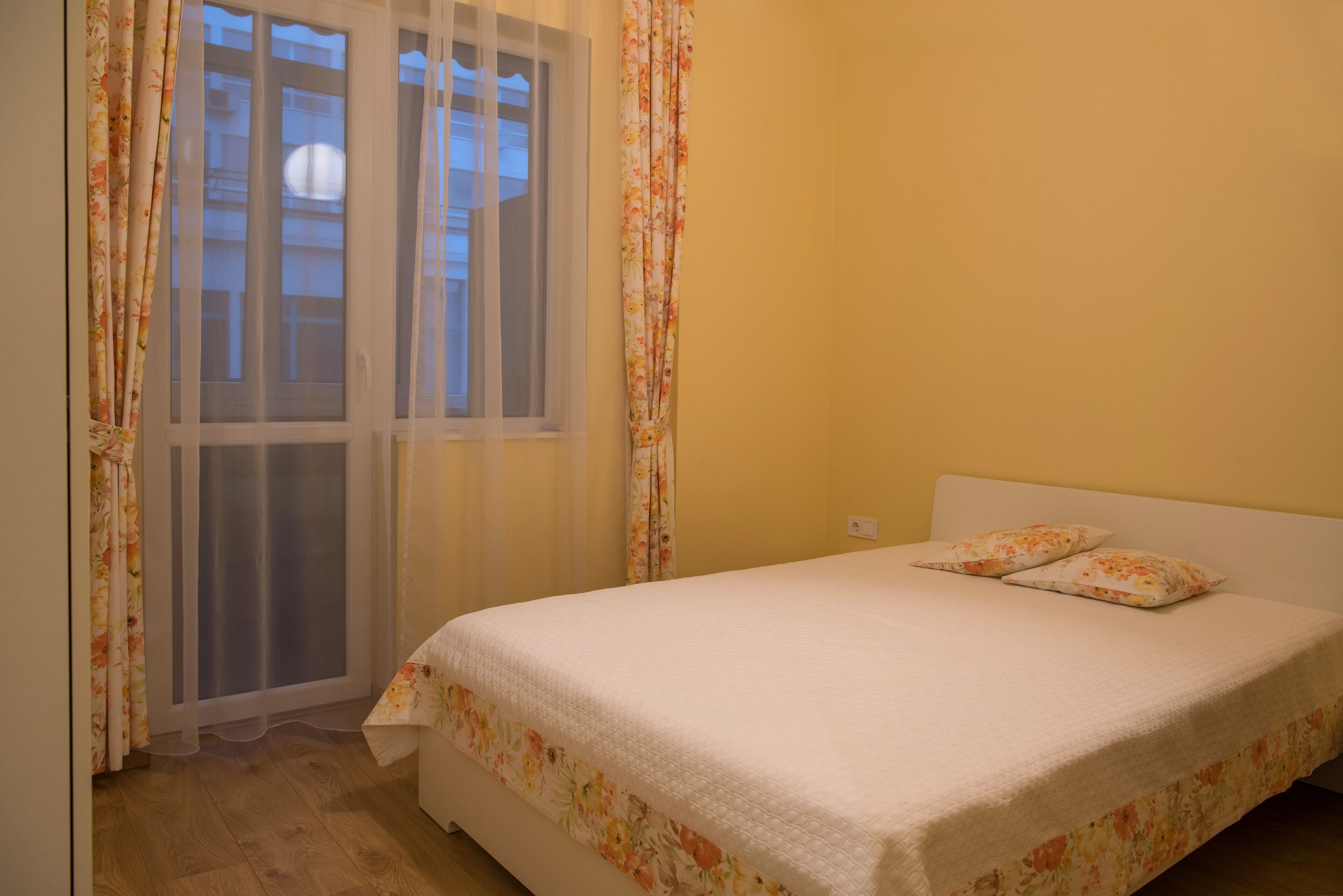 Un dormitorio con cama, cortinas con estampado floral y una ventana con persianas.