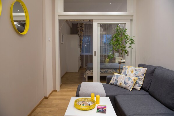 Una sala de estar moderna con un sofá gris, una mesita blanca y una cesta amarilla.