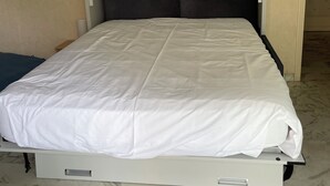 A bed with a white mattress and dark headboard, a bedside table, and a marble-patterned floor. - JUAN LES PINS STUDIO SEA VIEW (Juan Les Pins)