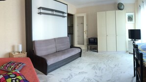 A room with a sofa, a small table with a lamp, a television, and a radiator. - JUAN LES PINS STUDIO SEA VIEW (Juan Les Pins)