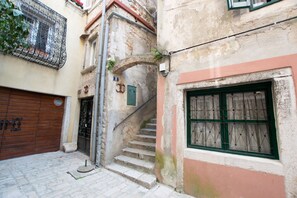 A narrow alleyway with a stone staircase leading to a door marked with a symbol.