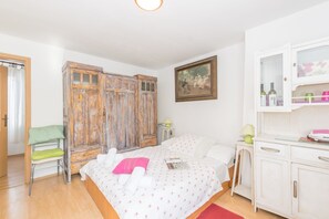 A bedroom with a bed, a wooden wardrobe, a desk with a lamp, and a painting on the wall. - Beautiful Rustical Apartment in Rovinj (Rovinj)