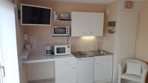 Une cuisine de taille réduite avec des meubles blancs, un four à micro-ondes, un grille-pain et un évier.
