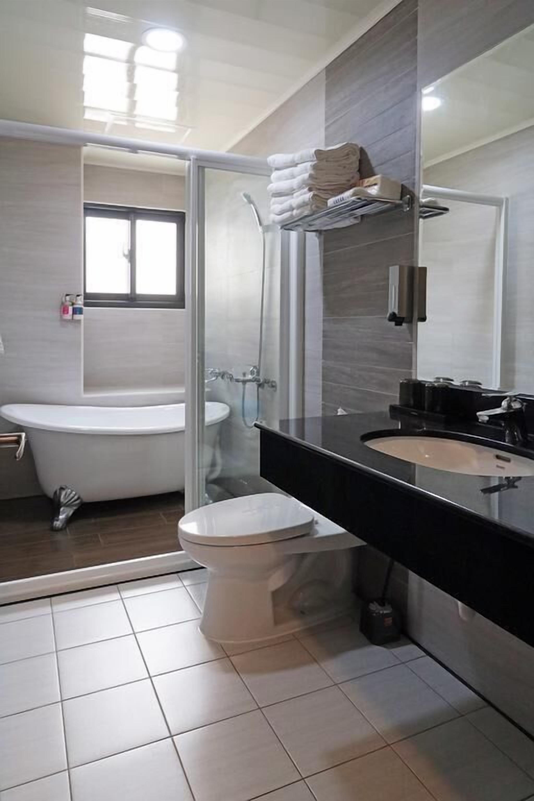 A modern bathroom with a bathtub, toilet, and a glass-enclosed shower area.