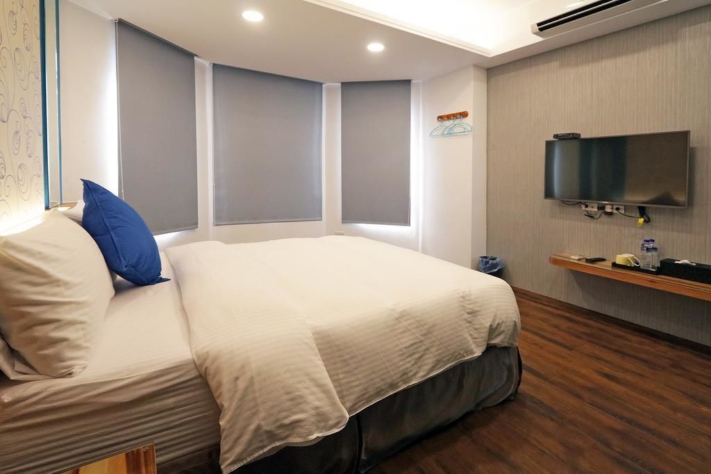 Habitación de hotel con una cama, un televisor montado en la pared y una ventana con vistas.