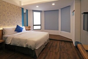 Un dormitorio con cama, mesita de noche, ventana y un banco empotrado.