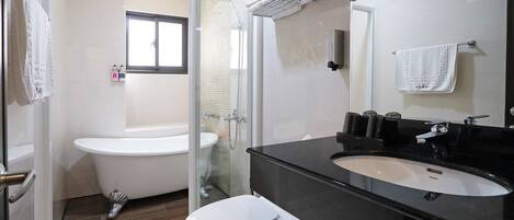 Un baño moderno con cabina de ducha de vidrio, inodoro blanco y lavabo sobre encimera negra.