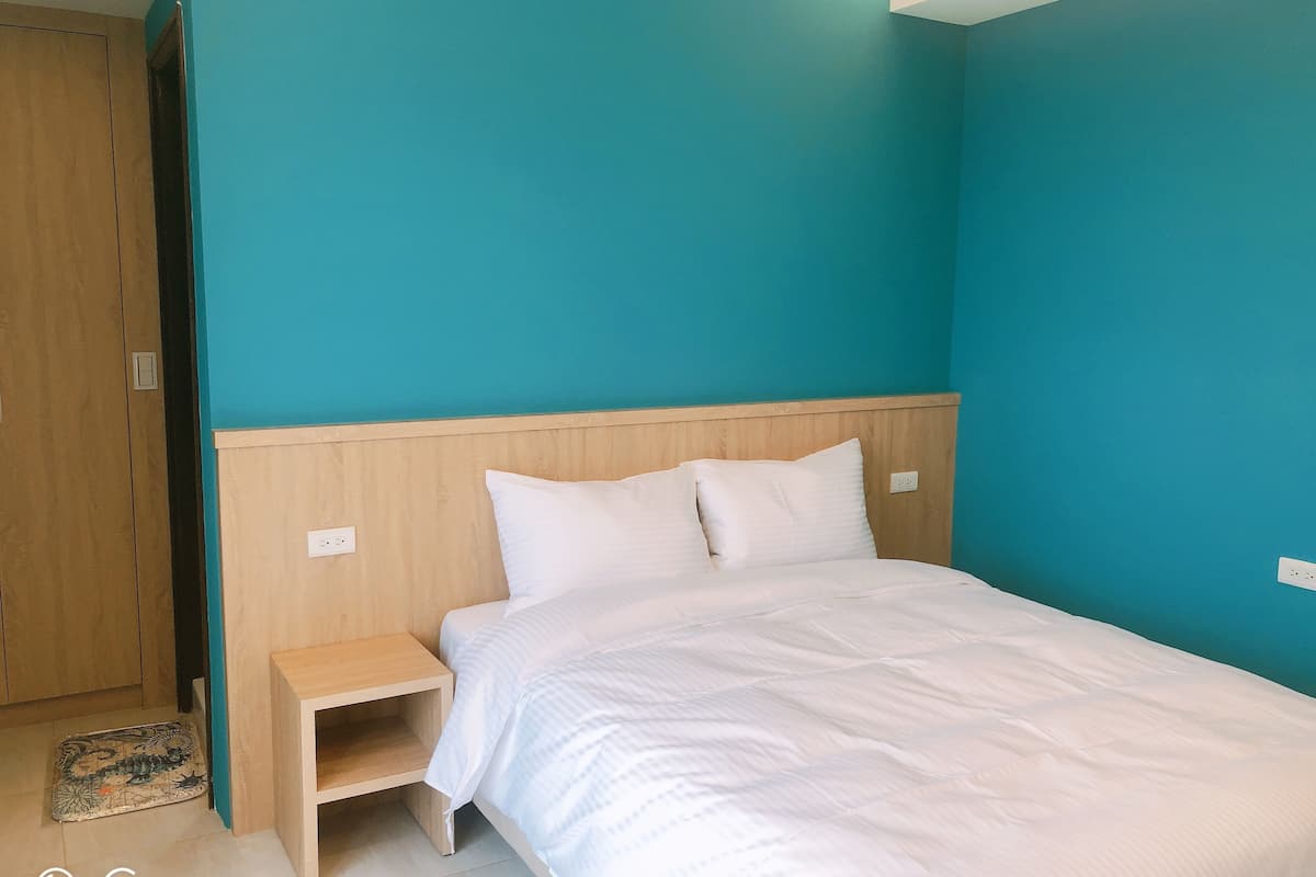 A bedroom with a bed, nightstand, and a wooden wardrobe.