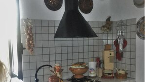 Ett kök med vita kakelväggar, träskåp och en svart köksfläkt.