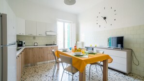 Une cuisine équipée d’une table à manger pour deux personnes, d’un four à micro-ondes et d’un téléviseur.