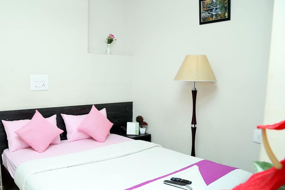 Una habitación de hotel con una cama, una mesita de noche, una lámpara y un cuadro colgado en la pared.
