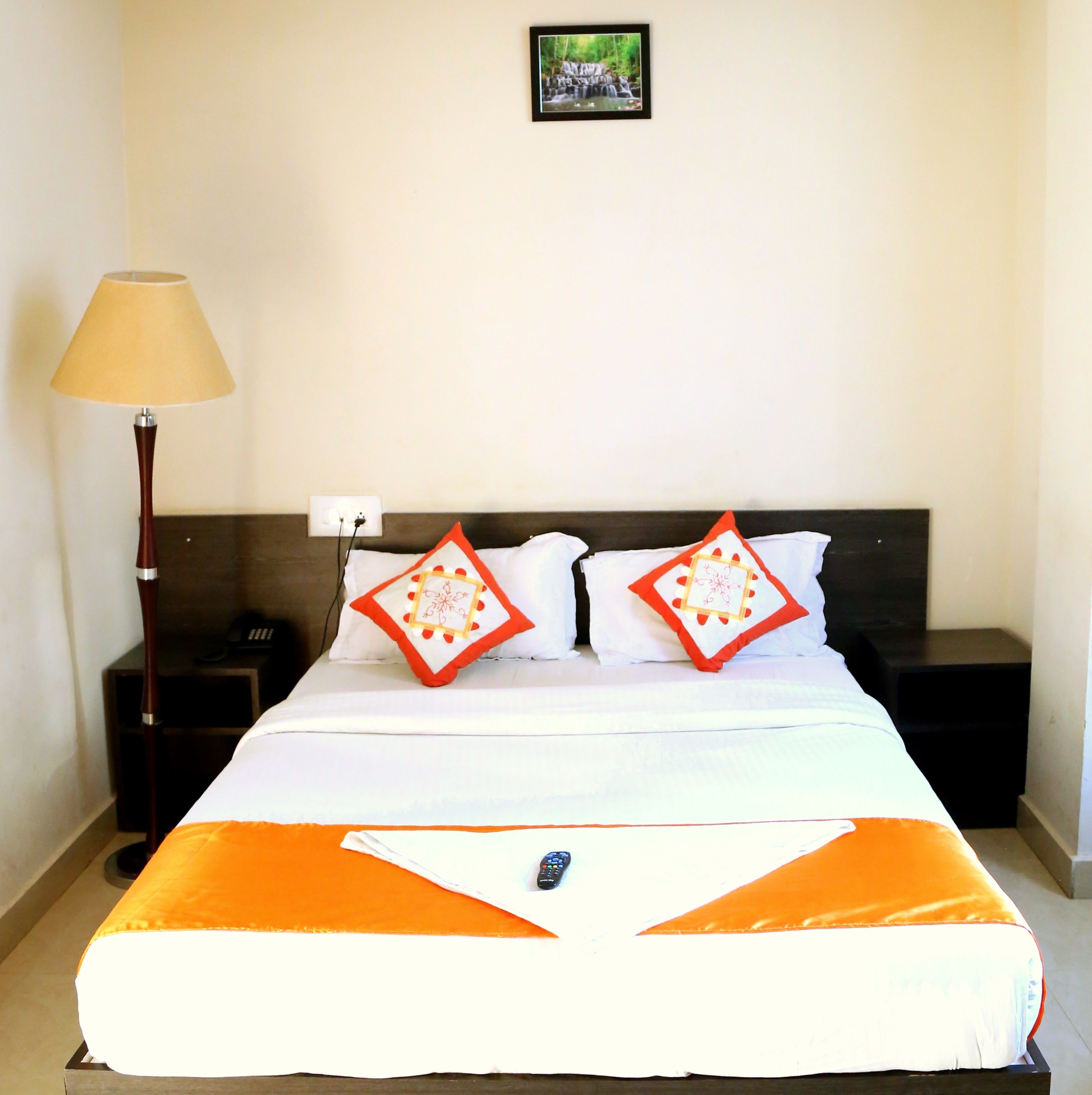 A hotel room with a bed, two nightstands, a lamp, and a picture on the wall.