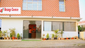 Um edifício com uma placa indicando "Orange Corner" e uma área de recepção com uma pessoa perto da entrada.