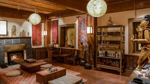 Ett traditionellt vardagsrum i japansk stil med en öppen spis, trämöbler och diverse dekorativa föremål.
