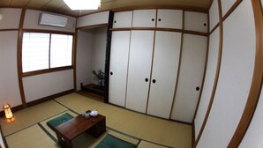 A traditional Japanese room with tatami flooring, a low wooden table with tea set, and sliding shoji doors. - Stay Omihachiman Ekimae Inn (Omihachiman)