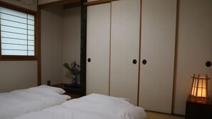 A traditional Japanese room with tatami flooring, a low wooden bed, and sliding doors. - Stay Omihachiman Ekimae Inn (Omihachiman)