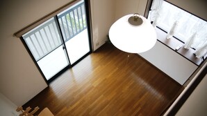 A room with wooden flooring, a ceiling light, and a view through a window with curtains. - Stay Omihachiman Ekimae Inn (Omihachiman)