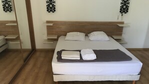 A neatly made bed with pillows and folded towels, a wooden headboard, and a mirror on the wall. - villa near Ajaccio with swimming pool in the heart of nature (Ocana)