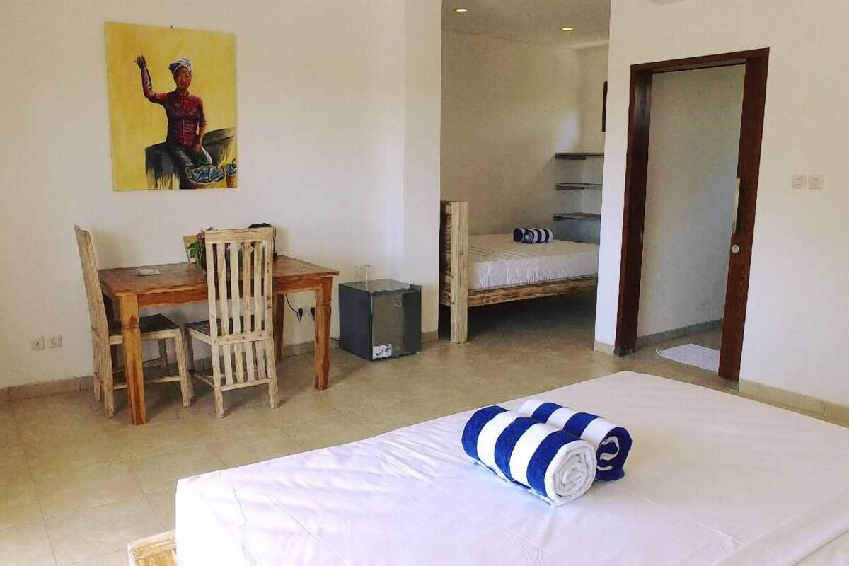 A room with a bed, a desk, a chair, a small table, and a bunk bed.