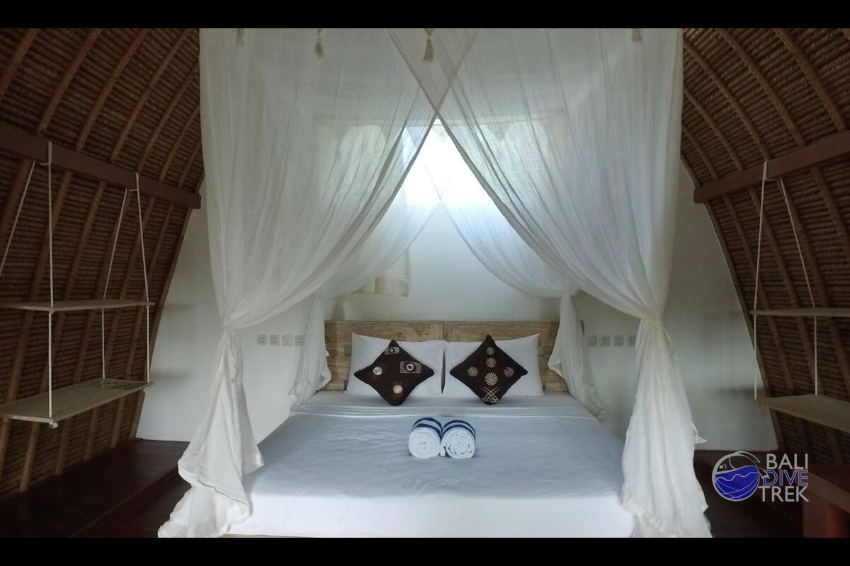 A bed with a canopy, two pillows with geometric patterns, and a shelf on the left.