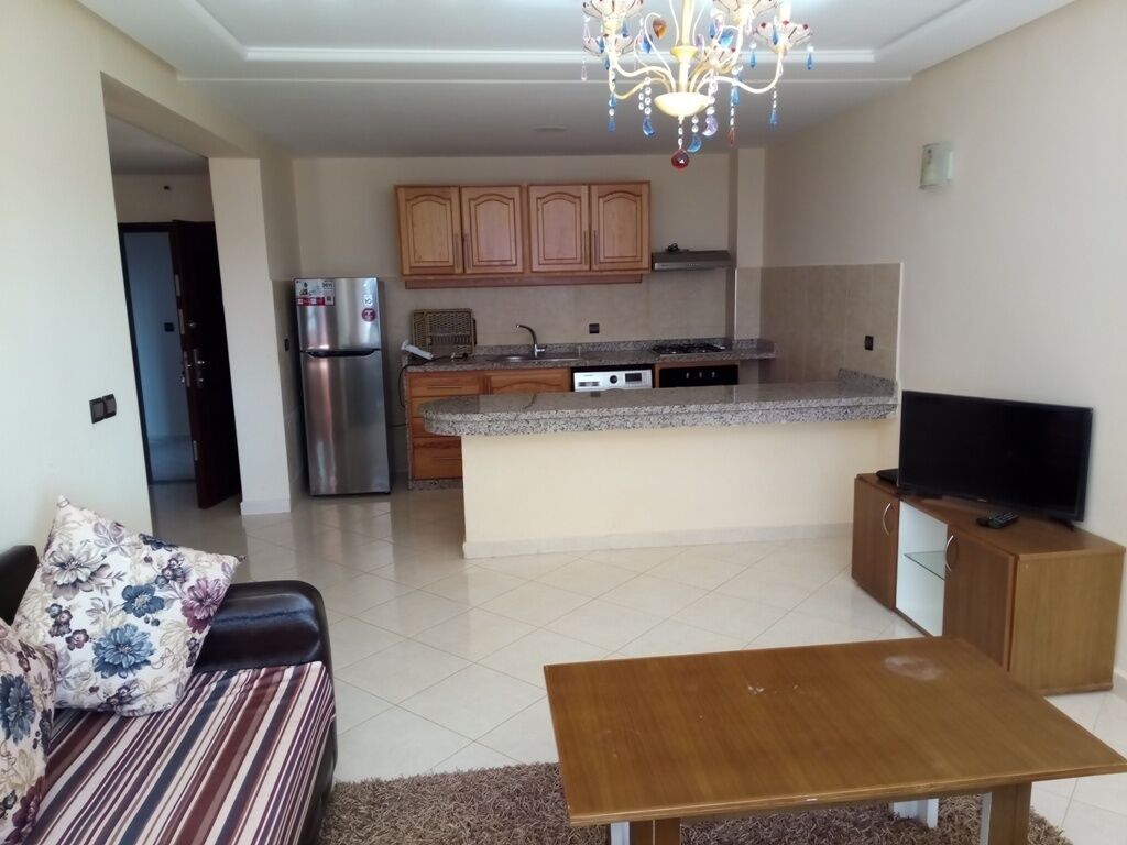 A modern kitchen with granite countertops, a built-in oven, and a stainless steel refrigerator.