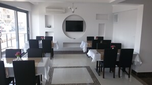 Un comedor moderno con mesas y sillas, un televisor de pantalla plana montado en la pared, y un suelo con diseño.