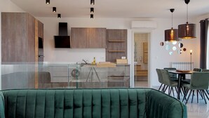 A modern kitchen with a glass island, wooden cabinets, and pendant lighting. - Istrian Pearl (Rasa)