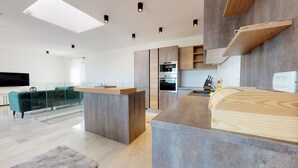 A modern kitchen with built-in appliances, a glass dining area, and a living space with a flat-screen TV. - Istrian Pearl (Rasa)