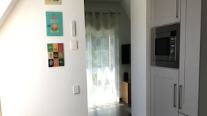 Une cuisine équipée d’un four à micro-ondes, de placards et d’une enseigne indiquant qu’on y sert du café, accrochée au mur.