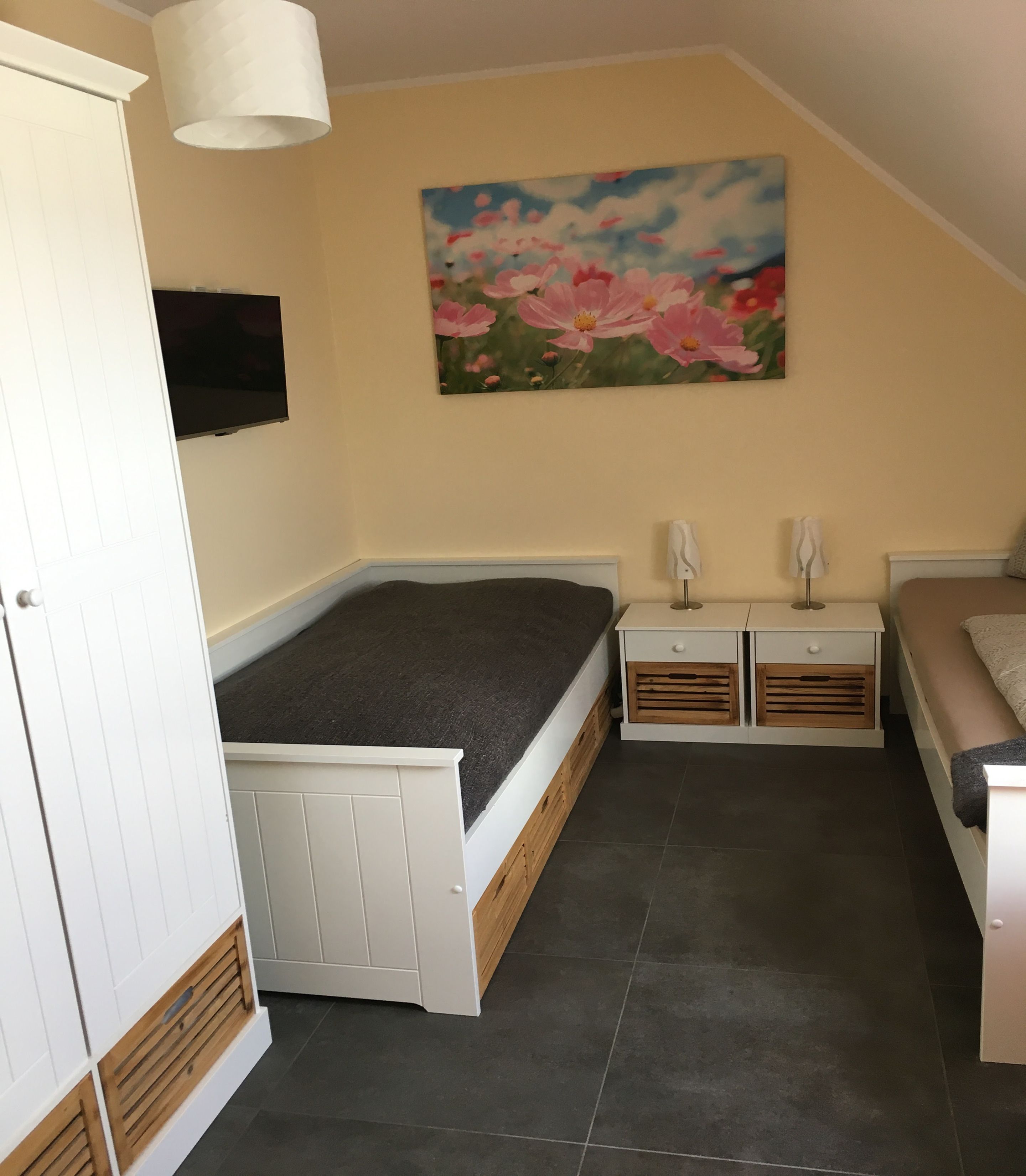 A compact bedroom with a bed, bedside tables, a wardrobe, and a painting on the wall.