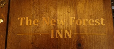 A wooden door with the text "The New Forest INN" engraved on it.