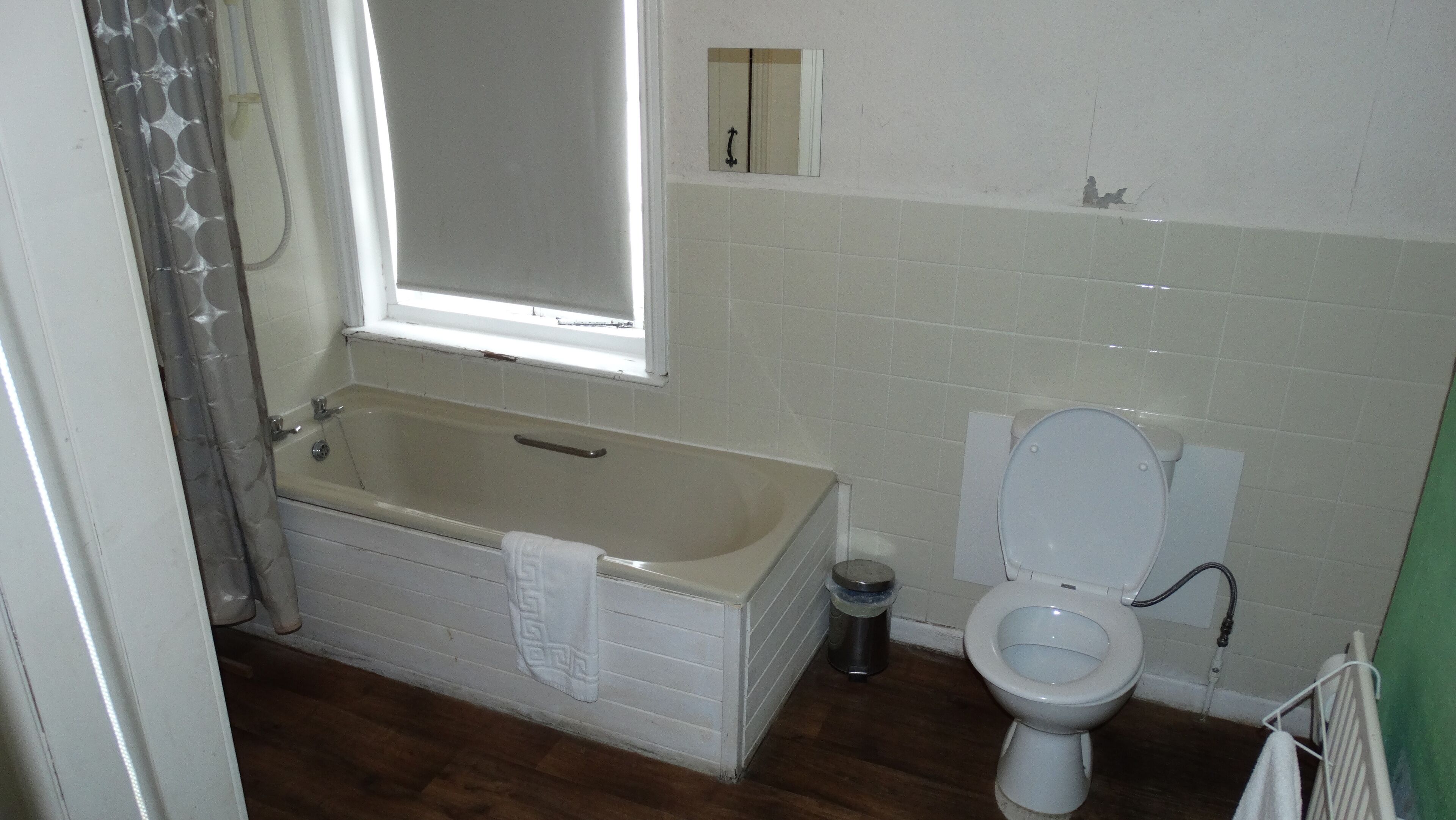 A bathroom with a bathtub, toilet, and a window.
