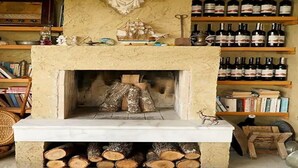 A cozy room with a fireplace, bookshelves, and wine bottles.