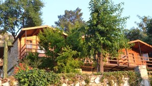 A rustic cabin with a stone foundation, wooden beams, and a balcony.